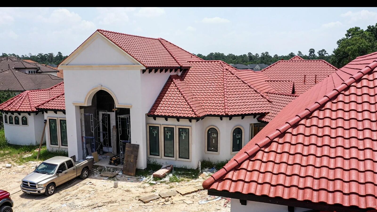 Tile roof installation in progress with crew truck on site